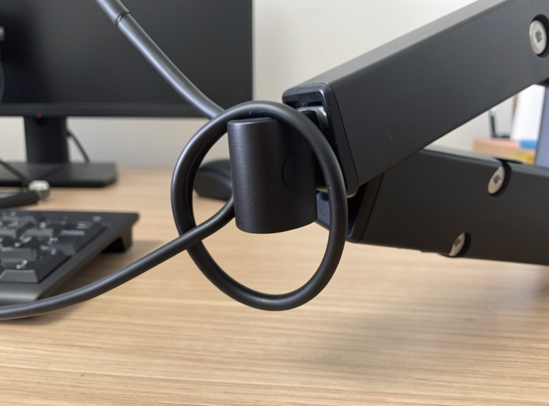 Monitor arm joint with a deliberate service loop of slack cable at the bend