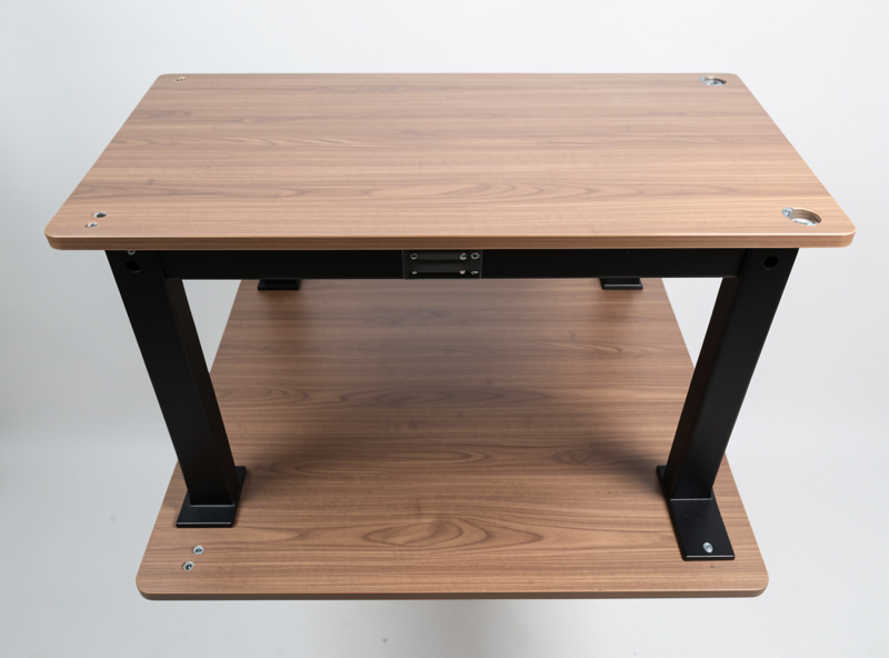 Underside view of a standing desk frame dry-fitted on an upside-down wooden desktop with screw holes marked