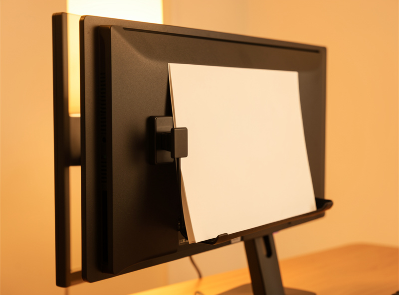 Monitor-mount clip document holder attached to the side of a screen holding a single page