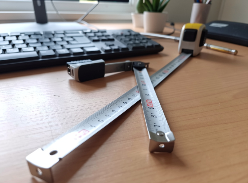 Tape measure across a desk beside a keyboard, measuring desk height from the floor