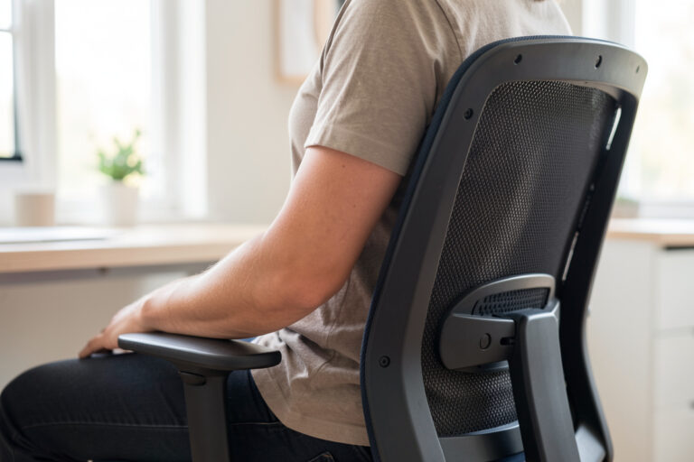 Seated person against ergonomic chair lumbar support, side profile