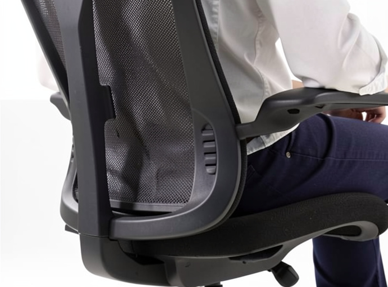 Side profile of a seated person against an ergonomic chair backrest showing the lower-back curve and lumbar contact point