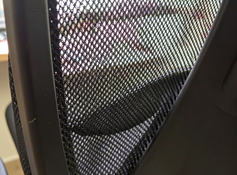 Close-up of a tensioned mesh office chair seat showing the weave and frame