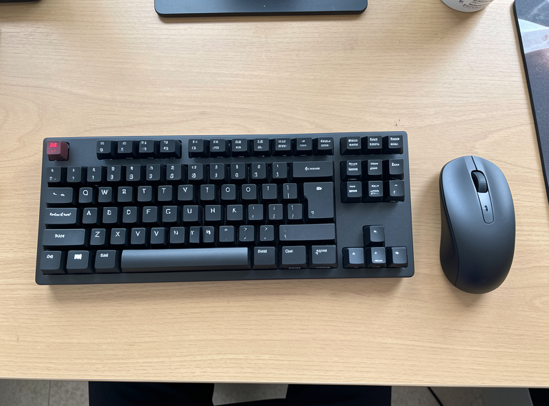 Tenkeyless mechanical keyboard on a desk with a mouse pulled in close beside it
