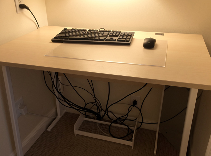 Tidy small apartment desk setup with cables routed into an under-desk tray and a clear work surface