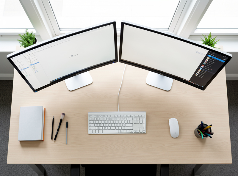 Top-down view of a balanced dual-monitor desk setup with weight distributed evenly